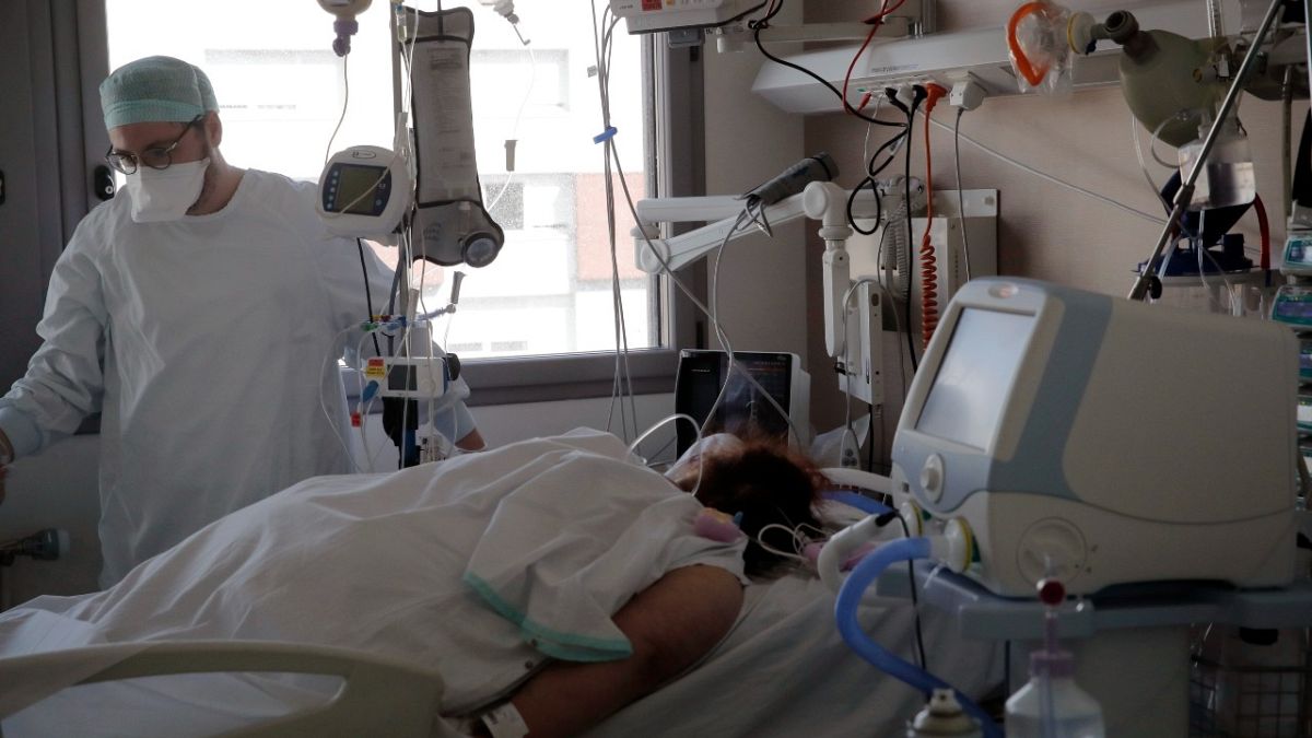 ممرض يعتني بمريضة في وحدة العناية المركزة في مستشفى شارل نيكول، في روان، فرنسا.