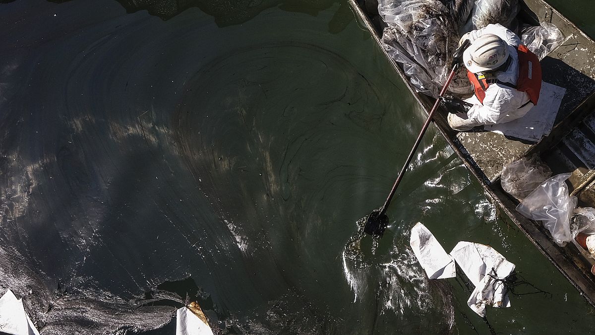 Workers in protective suits clean oil in an inlet leading to the Wetlands Talbert Marsh after an oil spill in Huntington Beach, Calif., on Tuesday, Oct. 5, 2021.