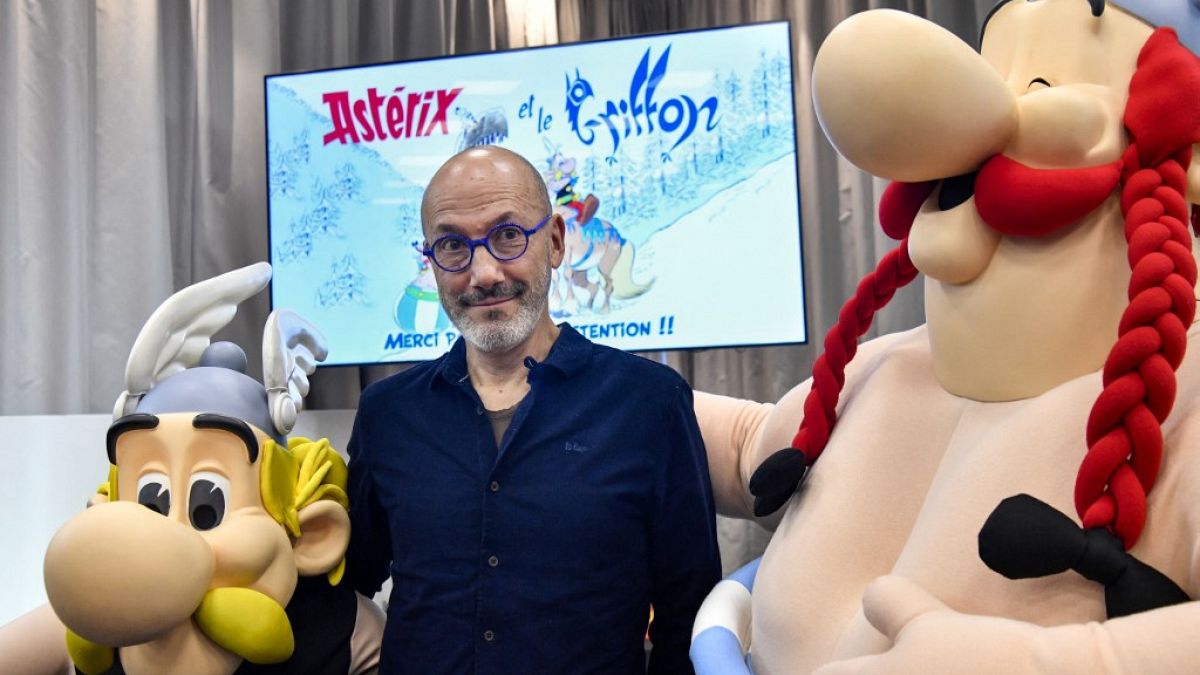 French writer Jean-Yves Ferri poses between effigies of Asterix and Obelix during the presentation of the new "Asterix" album in Paris, on October 11, 2021.