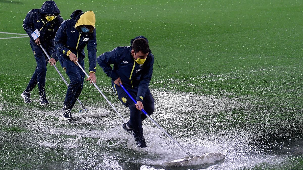 Villareal coaching staff clear water from the pitch following heavy rain before a UEFA Europa League group match
