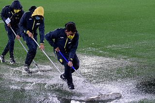 Villareal coaching staff clear water from the pitch following heavy rain before a UEFA Europa League group match