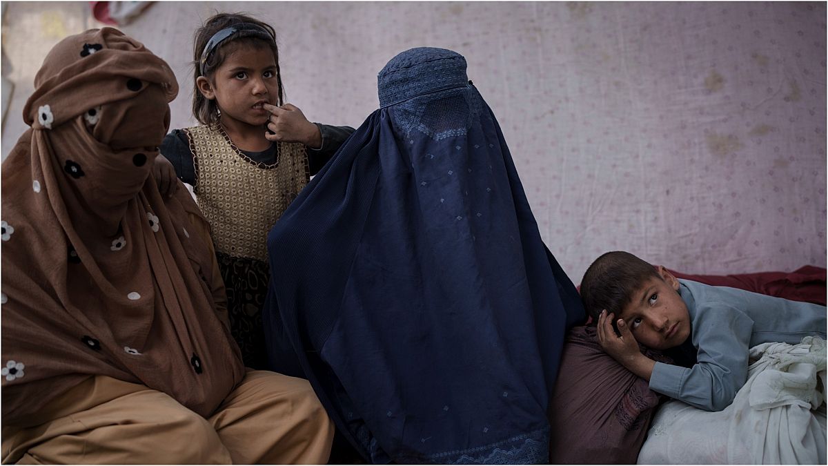 أمٌ أفغانية من ولاية قندوز (في الوسط)، تجلس مع أطفالها في مخيم للنازحين أثناء انتظارهم حافلة للعودة إلى ديارهم في كابول 9 تشرين الأول/أكتوبر 2021