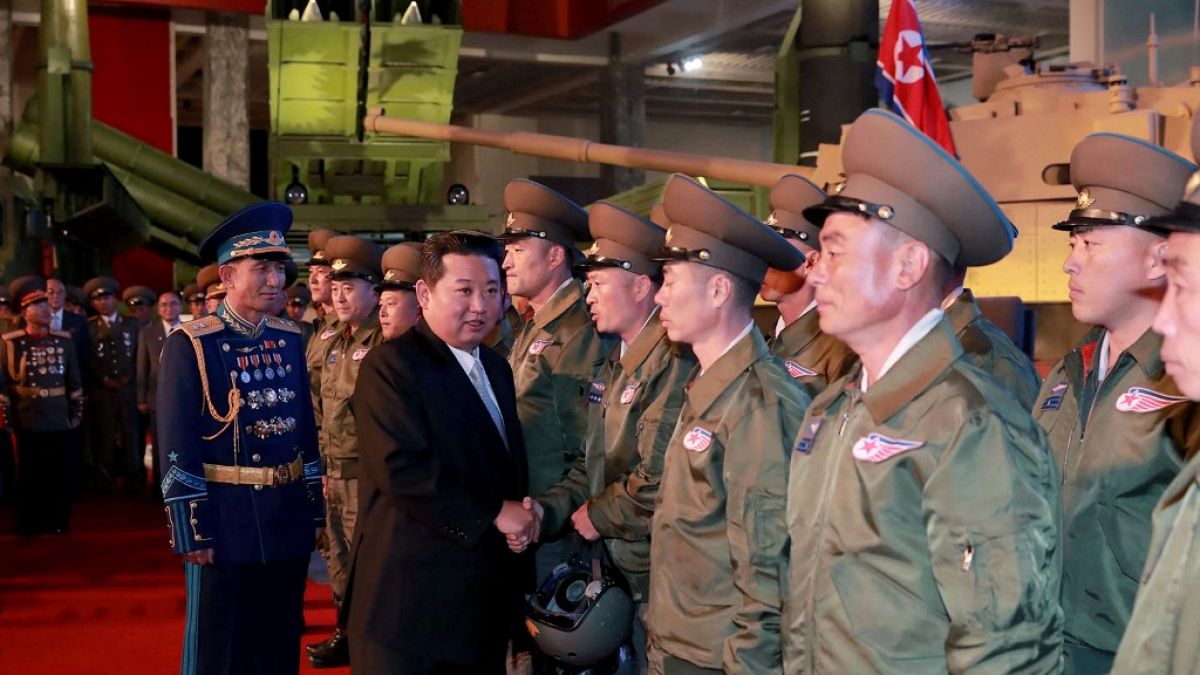 Kim Jong Un and senior officials standing next to missile.