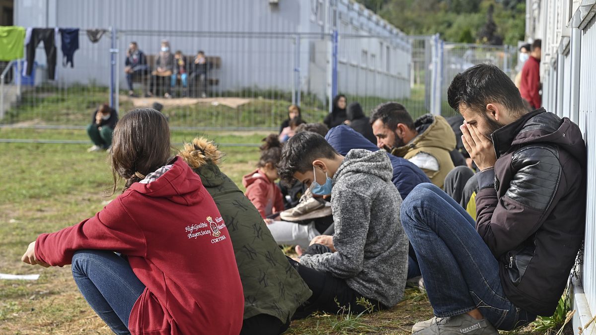 Migrants sit in front of containers at the Central Initial Reception Facility for Asylum Seekers, in Eisenhuettenstadt, Brandenburg, Germany, Oct. 6, 2021.