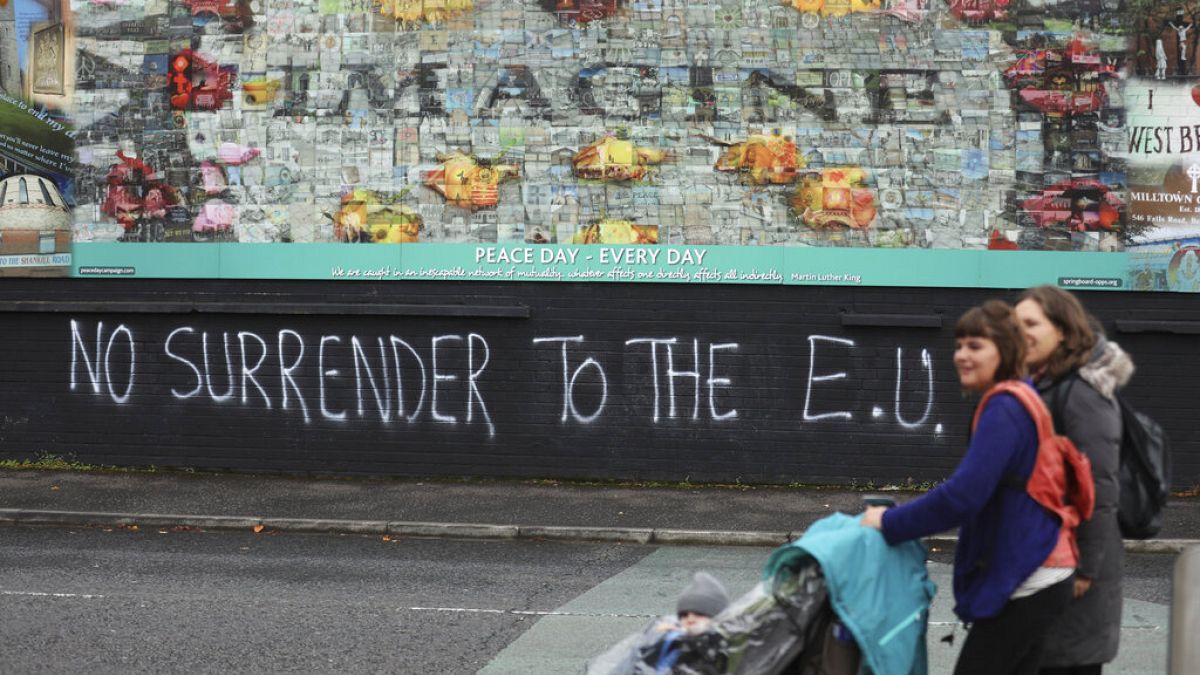 In this Monday Oct. 14, 2019 file photo people walk past pro-Brexit graffiti in West Belfast Northern Ireland. 