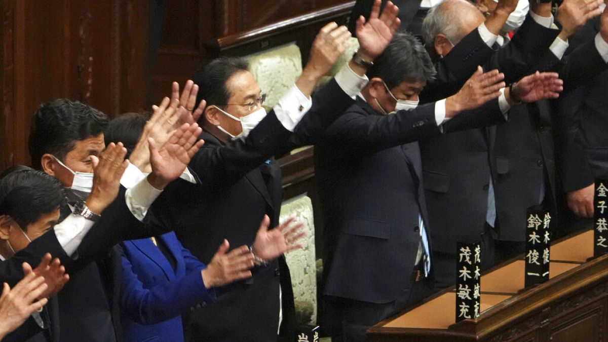 Japanese Prime Minister Fumio Kishida, center, and other lawmakers give three cheers after dissolving the lower house, the more powerful of the two parliamentary chambers.