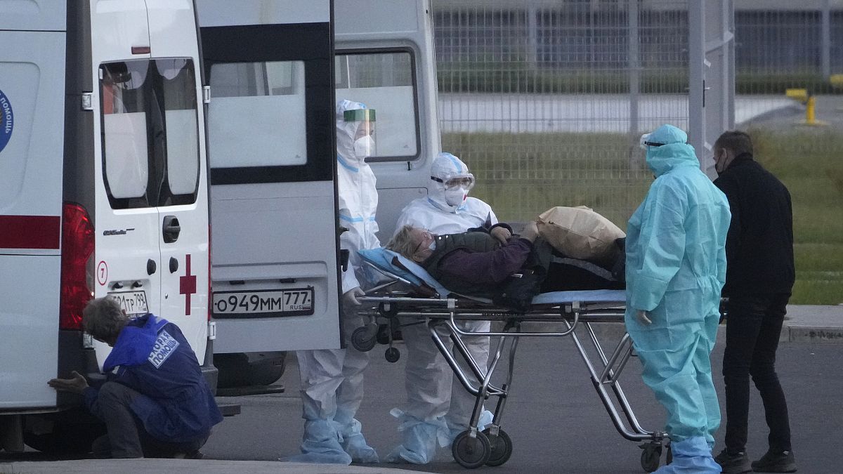 موظفون في قطاع الصحة في روسيا ينزلون مريضاً يشتبه بإصابته بـ"كوفيد-19" من سيارة الإسعاف لإدخاله إلى مستشفى كوموناركا قرب العاصمة موسكو