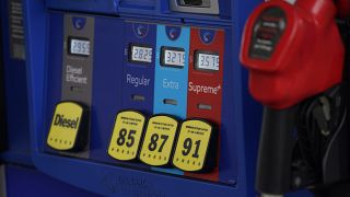 In this May 9, 2021, file photo prices are illuminated above the levers for the different grades of gasoline available at a pump at an Exxon station.