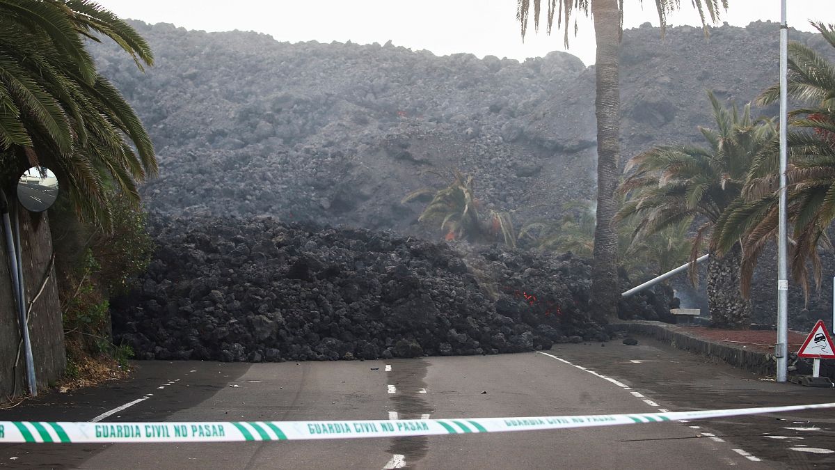 A Spanish Civil Guard tape is seen along a road blocked by lava spewed from the Cumbre Vieja volcano in La Laguna