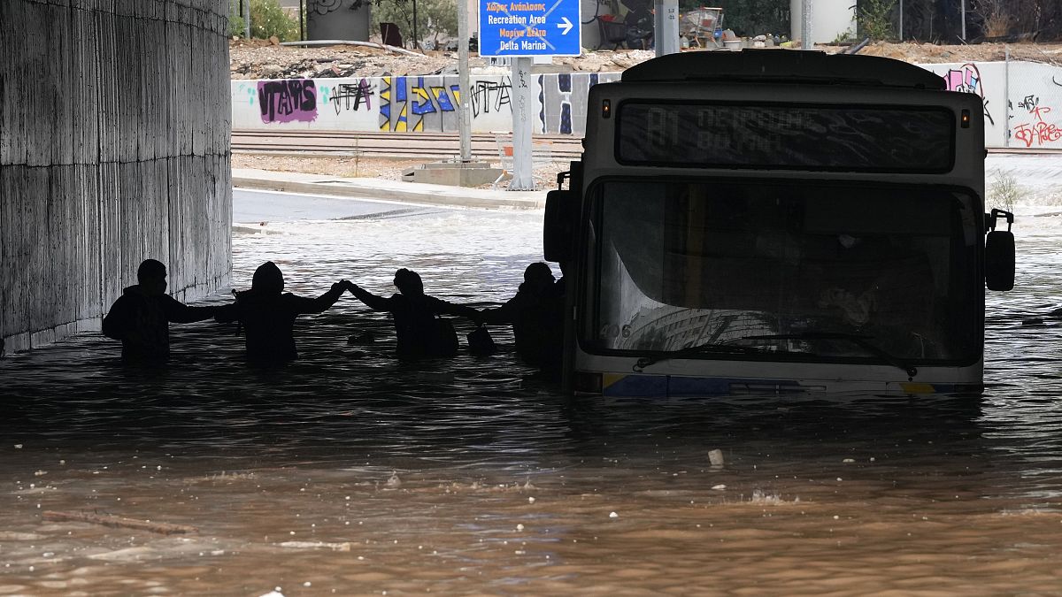 Passengers wade through high water after evacuating a bus stuck in a flooded underpass in southern Athens.
