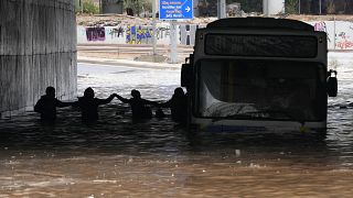 Passengers wade through high water after evacuating a bus stuck in a flooded underpass in southern Athens.