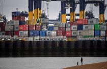 Shipping containers are seen as people walk on the beach near the Port of Felixstowe, east of London.