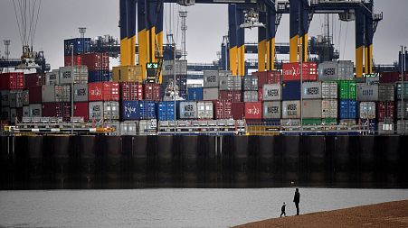 Shipping containers are seen as people walk on the beach near the Port of Felixstowe, east of London.