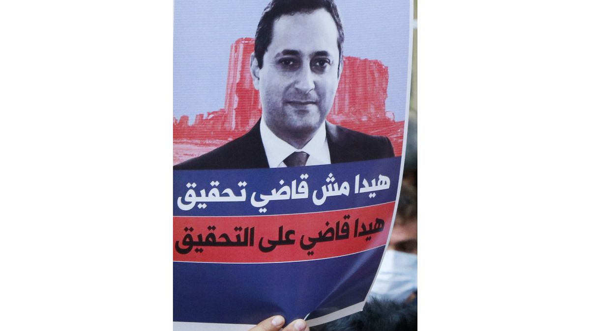 متظاهرة تحمل ملصقًا يظهر صورة للقاضي طارق بيطار، الكلف بالتحقيق حول انفجار مرفأ بيروت.