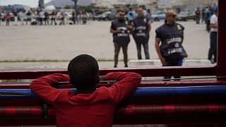پسر بچه پناهجو در مدیترانه از درون قایق به ماموران فرانسوی می‌نگرد