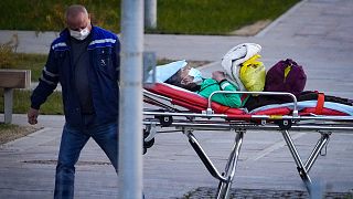 A medical worker carries a patient suspected of having coronavirus on a stretcher at a hospital in Kommunarka, outside Moscow, Russia, Monday, Oct. 11, 2021. 