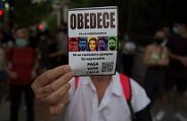 A woman holds a pamphlet reading "Obey" during a demonstration against the increase of the household electricity bills in Granada, on September 19, 2021