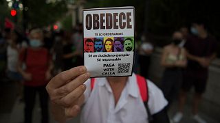 A woman holds a pamphlet reading "Obey" during a demonstration against the increase of the household electricity bills in Granada, on September 19, 2021