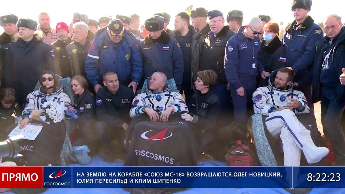 Russian space agency cosmonaut Oleg Novitskiy, centre, actress Yulia Peresild, left, and film director Klim Shipenko sit in chairs shortly after landing in Kazakhstan.