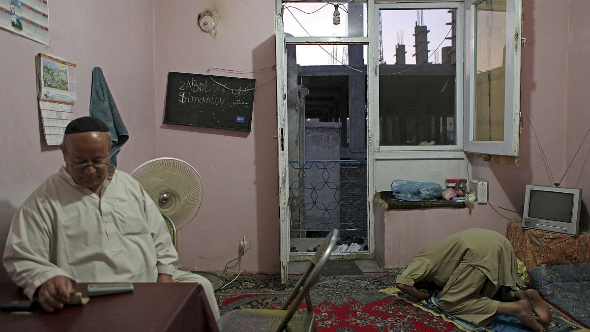 زبولون سيمينتوف يجلس على طاولة غرفة الطعام في منزله في كابل بينما يصلي بقربه صديقه المسلم شيرغول أميري. 2021/04/05