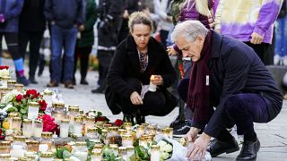 Norway's Prime Minister Jonas Gahr Støre lays flowers and lights candles during his visit to Kongsberg, Norway, Friday, Oct. 15, 2021