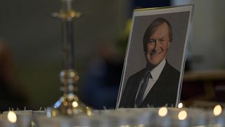 Candles are lit next to a portrait of British Lawmaker David Amess during a vigil for him at St Michaels Church, in Leigh-on-Sea, England Sunday, Oct. 17, 2021.