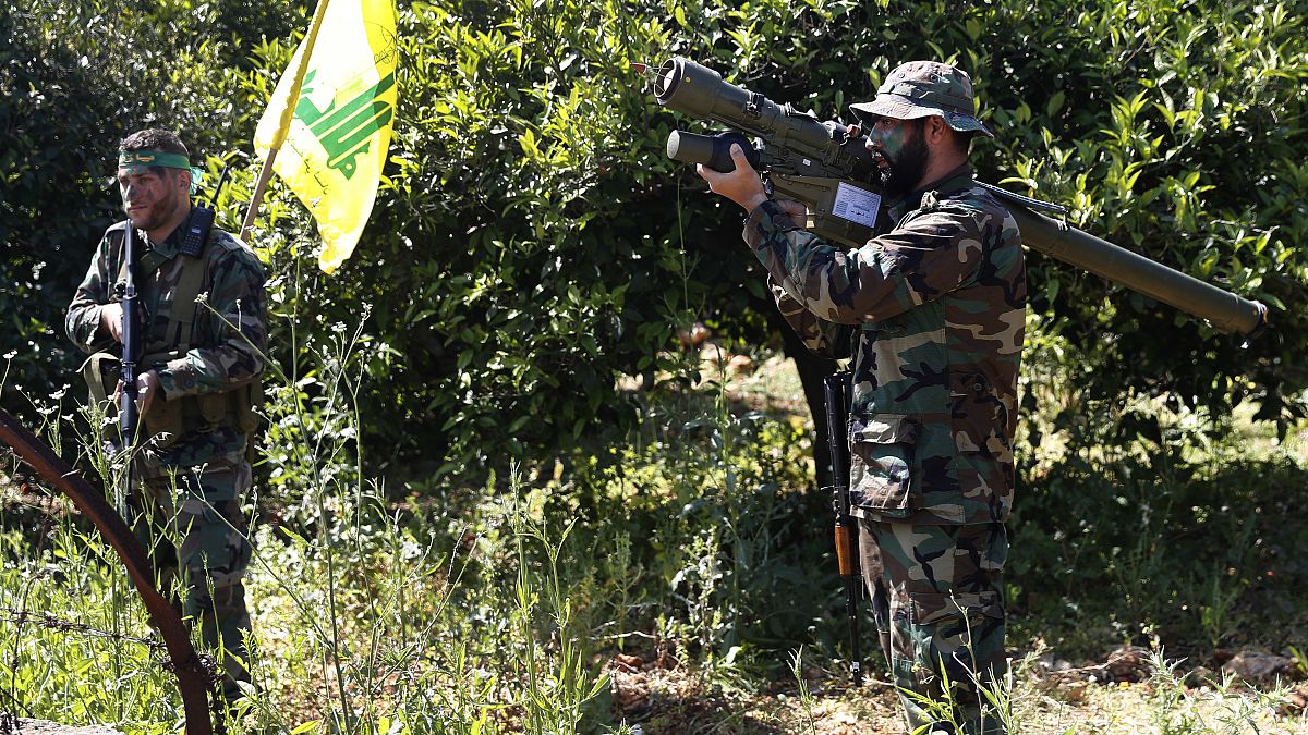 مقاتل من حزب الله يحمل صاروخًا إيرانيًا مضادًا للطائرات مع رفيقه بين أشجار البرتقال في بلدة الناقورة، جنوب لبنان. 2017/04/20