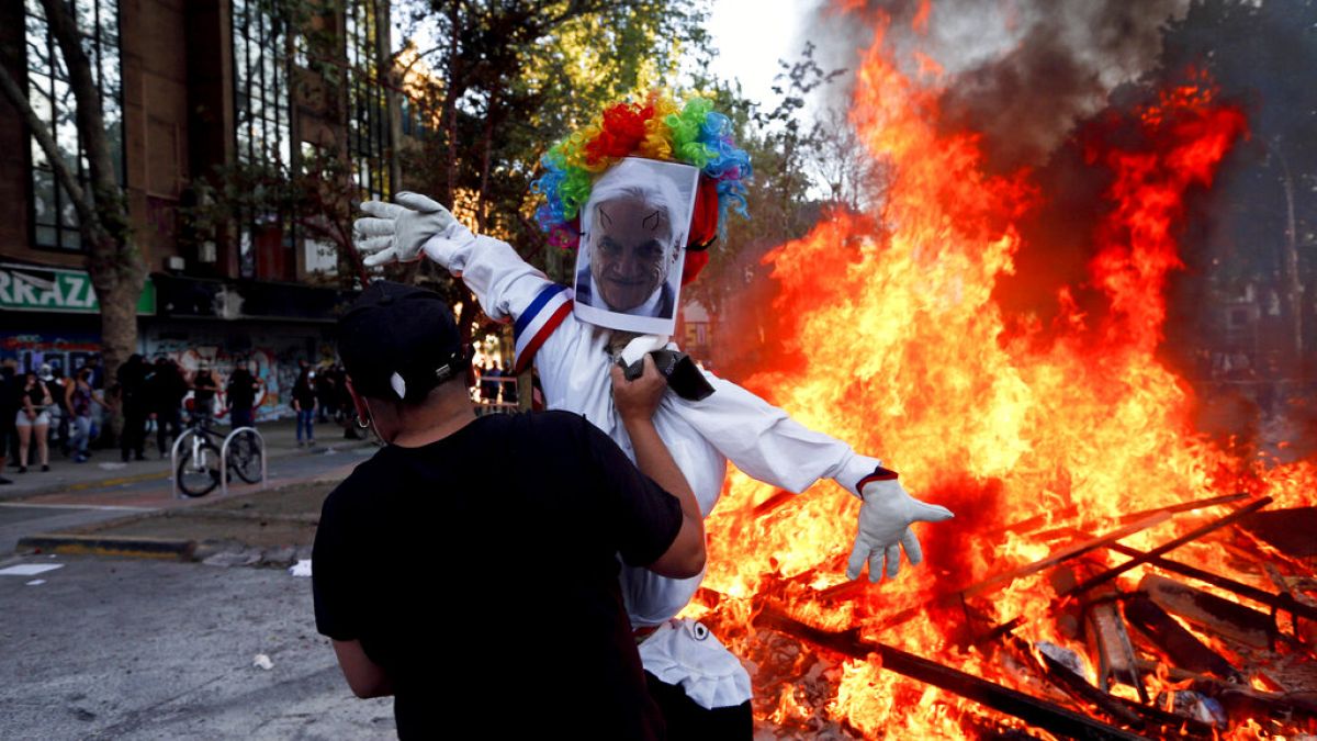 Un manifestante con un muñeco que representa al presidente chileno, Sebastián Piñera