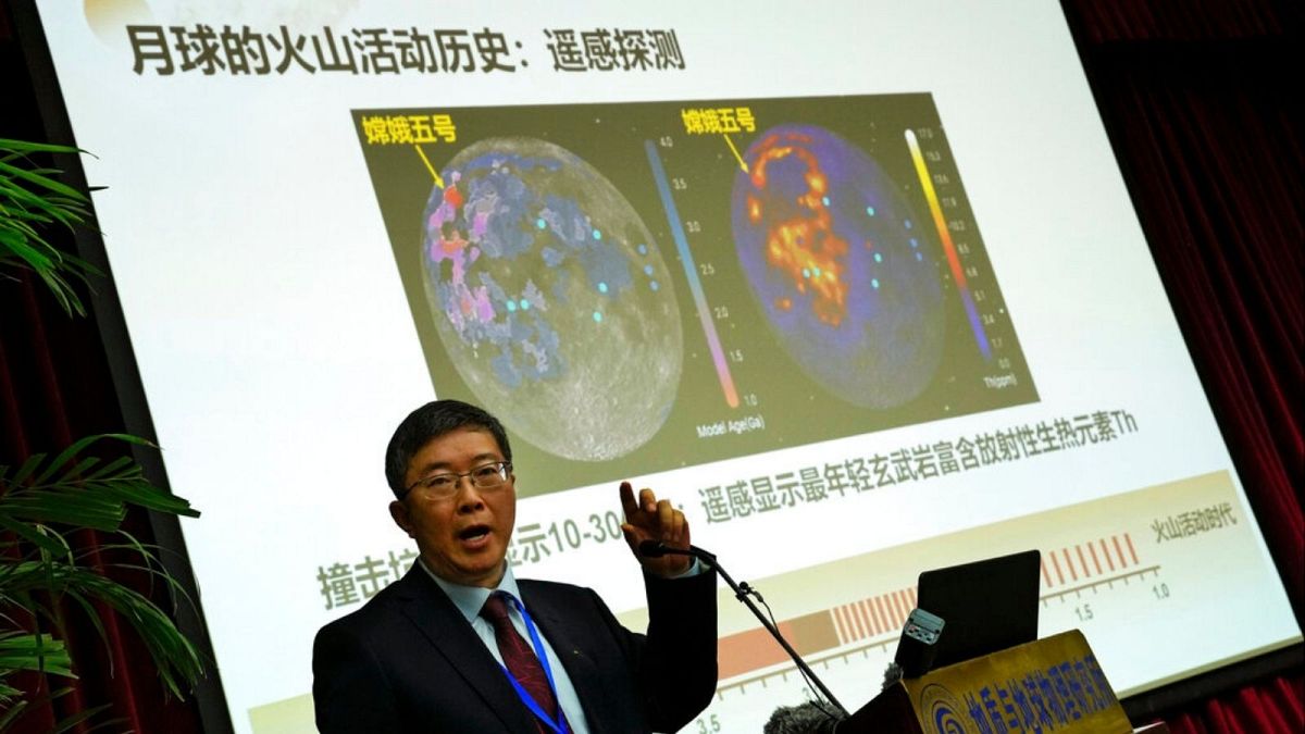 Li Xianhua speaks near a screen showing the volcano activities on the moon