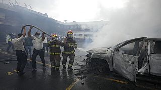 Los bomberos y la policía colaboran para sofocar con agua un vehículo incendiado, 19/10/2021, Guatemala, Guatemala