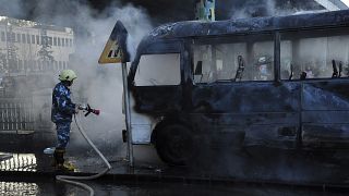 A Syrian firefighter extinguishes a burned bus at the site of a deadly explosion, in Damascus, Syria, 20 Oct. 2021.
