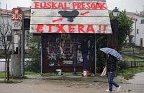 Une femme passe devant un arrêt de bus sur lequel on peut lire en basque "ETA" à gauche et "Prisonniers basques, rentrez chez vous"