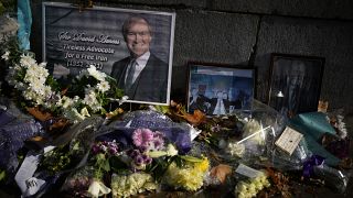 Floral tributes and pictures of British MP David Amess outside the Houses of Parliament in London.