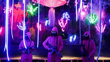 Staff members wearing "Squid Game" costumes stand guard at Strawberry Cafe in Jakarta, Indonesia, October 15, 2021.