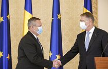 Nicolae Ciuca (izquierda) da la mano al presidente rumano, Klaus Iohannis