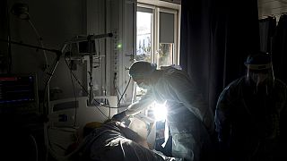 Chief of ICU department Dr. Valentyn Koroliuk speaks to a patient with coronavirus at the city hospital 1 in Rivne, Ukraine, Friday, Oct. 22, 2021.