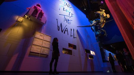 Visitors pose by a life-sized version of Pink Floyd's 'The Wall' at the V&A Museum in London, UK