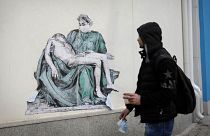 A man passes by replica of Michelangelo's Pieta painted on the wall of Pirogov hospital in Sofia, Sunday, Feb. 7, 2021