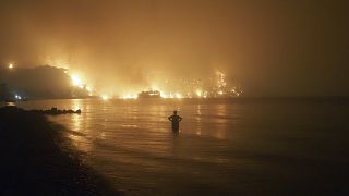 رجل يشاهد حرائق الغابات تقترب من شاطئ كوتشيلي في شمال أثينا، اليونان.