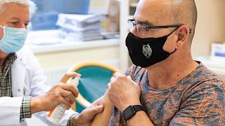 Kornafeld János szülész-nőgyógyász főorvos lefertőtleníti egy férfi vállát, mielőtt beoltja a Pfizer-BioNTech vakcinájával.