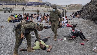 Солдаты армии Испании и группа нелегальных мигрантов в полуэкславе Сеута на границе с Марокко 