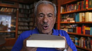 محمد سالم النوري ينفض الغبار عن كتاب في مكتبة دار المعرفة، التي اضطر لإغلاقها عام 2000 بسبب ضعف المبيعات وتزايد التكاليف، في العاصمة السورية دمشق، في 12 أكتوبر 2021