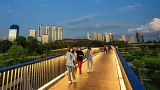 People walk on an elevated path called the "Skywalk" at Benjakitti Park in Bangkok, Thailand.