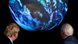 El primer ministro británico, Boris Johnson, a la izquierda, y David Attenborough observan una proyección del planeta Tierra durante la presentación de la próxima COP26.