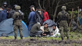 In this Sept. 1, 2021 file photo, migrants are seated, after crossing the border from Belarus into Poland in the village of Usnarz Gorny, Poland.