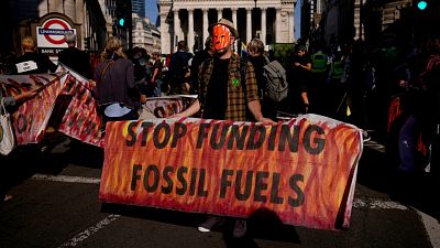 climate change activist holds a banner backdropped by the City of London financial district. climate change activist holds a banner backdropped by the City of London financial district.