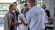 A security person scans COVID-19 certificates of attendees of a political party gathering in Ljubljana, Friday, Sept. 10, 2021.