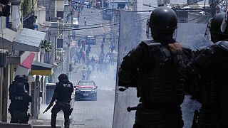 La policía observa a los manifestantes retirarse, en Quito, tras lanzarles gases lacrimógenos, en el segundo día de protestas en Ecuador.
