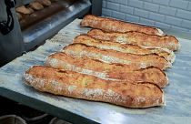 Baguettes are removed from the oven at Feru bakery in Louveciennes, west of Paris, Tuesday, Oct. 26, 2021.