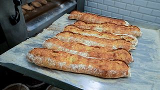 Baguettes are removed from the oven at Feru bakery in Louveciennes, west of Paris, Tuesday, Oct. 26, 2021.